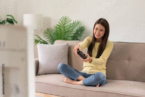 Leisure activity concept, Young woman sitting on couch to control joystick while playing video game