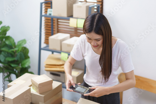 Online selling concept, Asian business women take a picture while packing product into parcel box