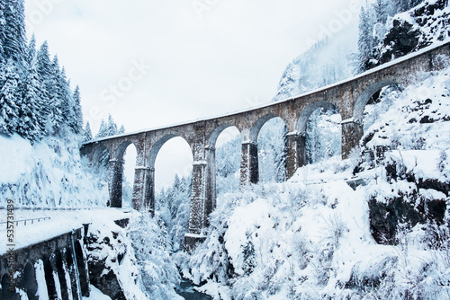 Mountain landscape with Sainte Marie bridge covered with snow in Les Houches, Chamonix valley, Eastern France. Viaduct bridge built to carry a railway over water.