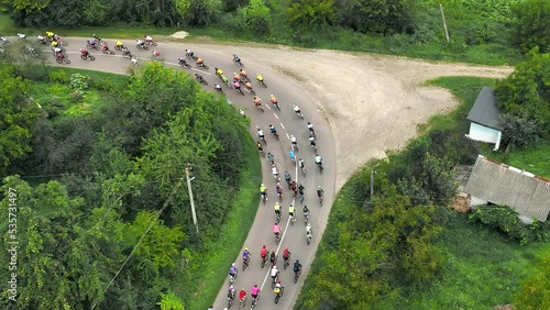 Aerial view A peloton of cyclists enters a sharp turn in the countryside. Overcoming the marathon distance on a bicycle by a group of cyclists.