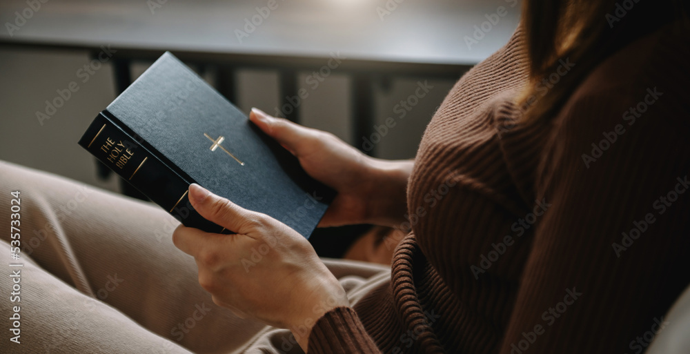 Woman sitting and praying holding a Holy Bible pray to God.