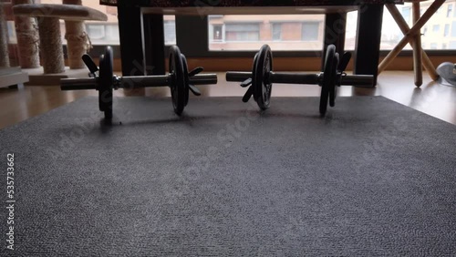 A dolly shot moving towards two dumbbells standing on a black yoga mat. photo