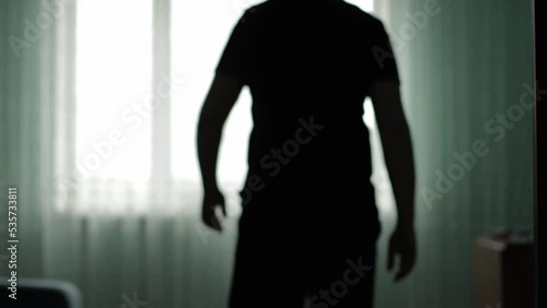 The man opens the swing doors and enters the room and looks out the window, background photo
