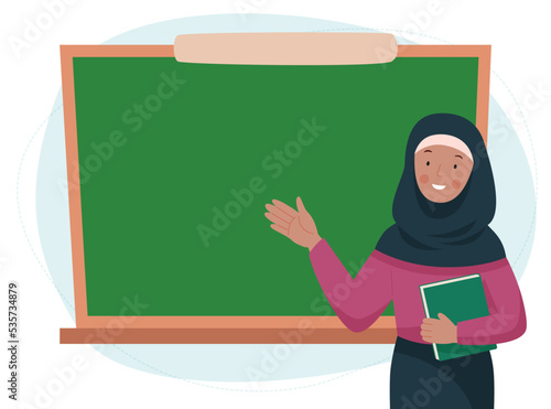 Female teacher in classroom. Muslim woman in a hijab showing something on a chalkboard. School and learning concept. Teachers day. 
