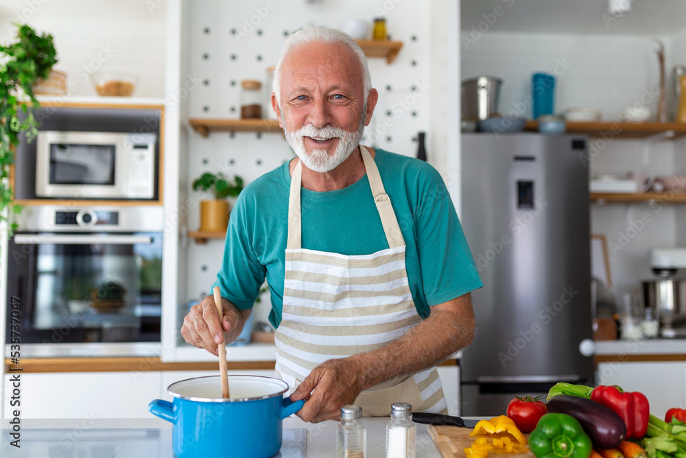 Happy senior man having fun cooking at home - Elderly person preparing health lunch in modern kitchen - Retired lifestyle time and food nutrition concept Happy senior man having fun cooking at home - Elderly person preparing health lunch in modern kitchen - Retired lifestyle time and food nutrition concept