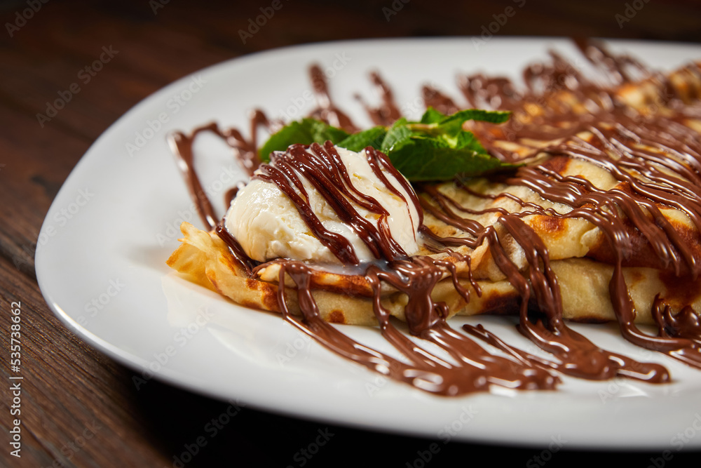 Pancake with a scoop of ice cream and chocolate. Close-up, selective focus