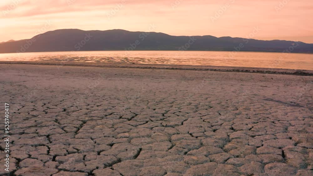 Cracked dry dirt in front and remains of lake in background reflecting blue sky and some clouds. Cracked dry dirt in front and remains of lake in background reflecting blue sky and some clouds.