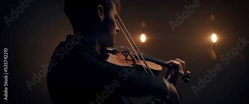 Photos WIDE young aspiring musician playing violin on a stage of a large venue