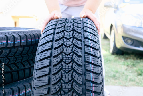 Woman changing car tire. Woman putting hand on new wheel tire. Female holding a tire and standing next to a piles of tires