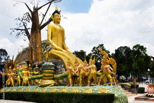 Golden big buddha image statue of Wat Maniwong for thai people travel visit tunnel cave and respect praying blessing holy worship mystical naga naka statue at Mani Wong temple in Nakhon Nayok Thailand photo