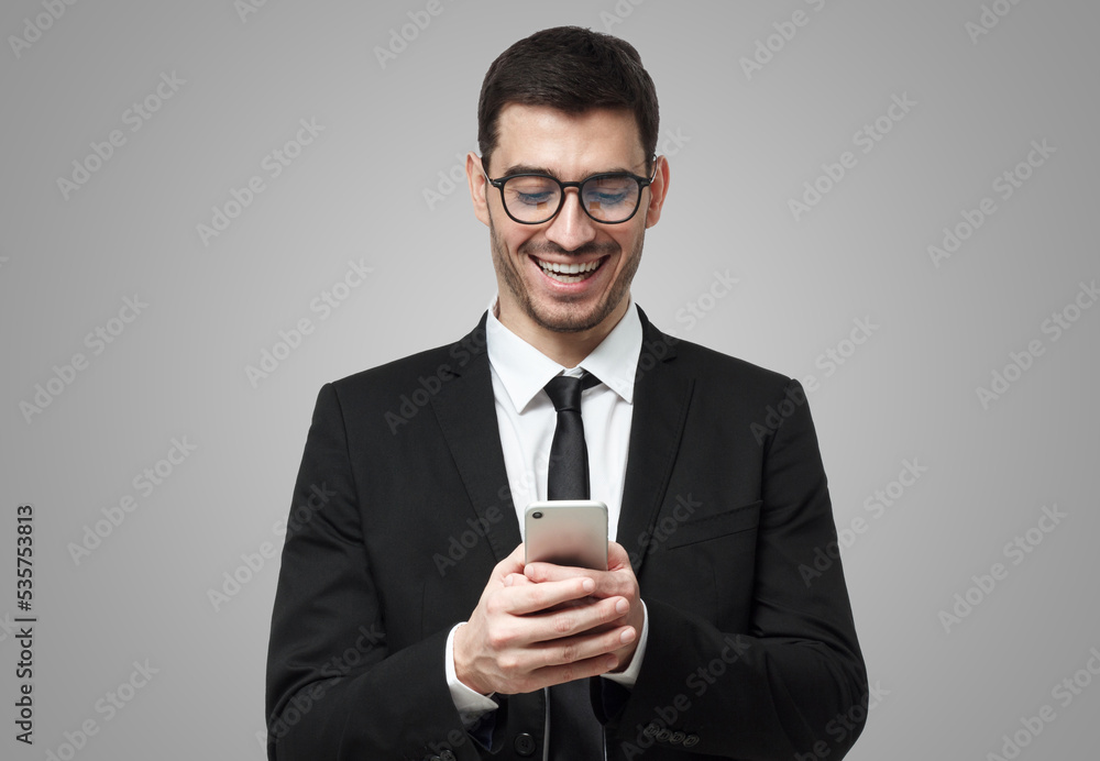 Young business man laughing, looking at mobile phone display, holding his phone with both hands Young business man laughing, looking at mobile phone display, holding his phone with both hands