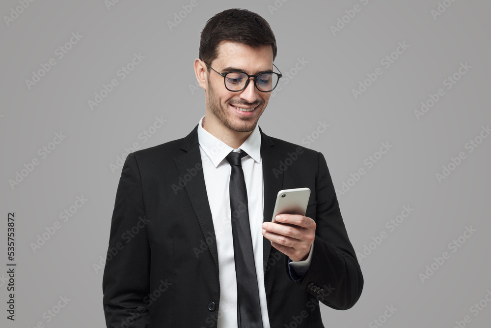 Young successful joyful sales manager typing message on his phone with one hand Young successful joyful sales manager typing message on his phone with one hand