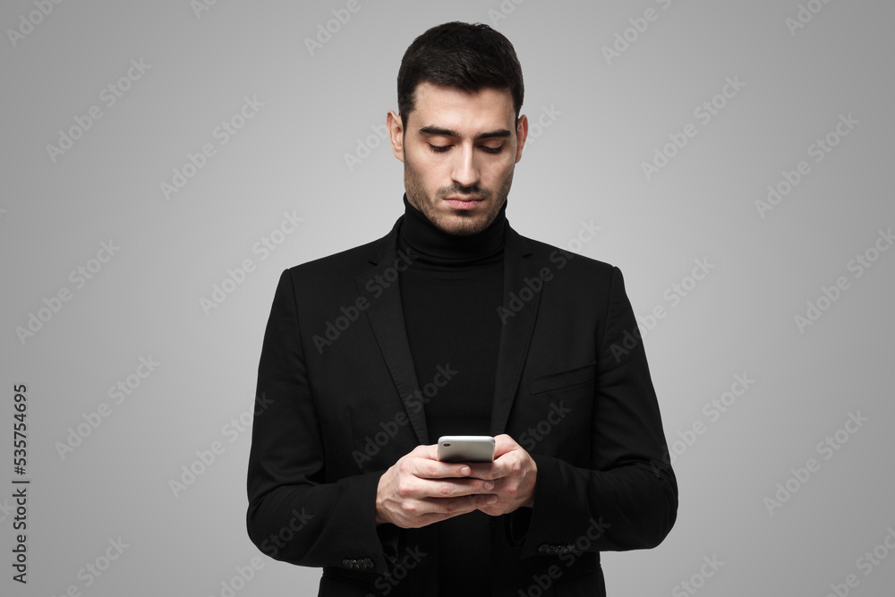 Male in black clothes holding phone, typing or browsing with concentrated face Male in black clothes holding phone, typing or browsing with concentrated face