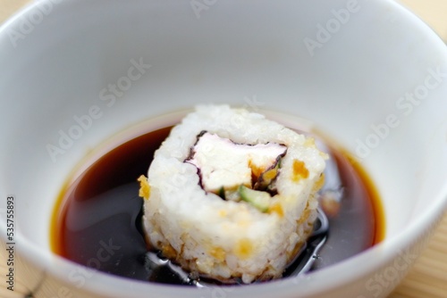 Japanese food roll in a soy sauce bowl on a bamboo mat