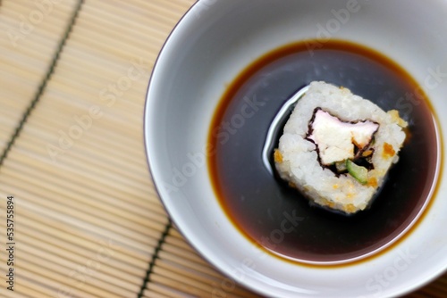 Japanese food roll in soy sauce bowl on a bamboo mat