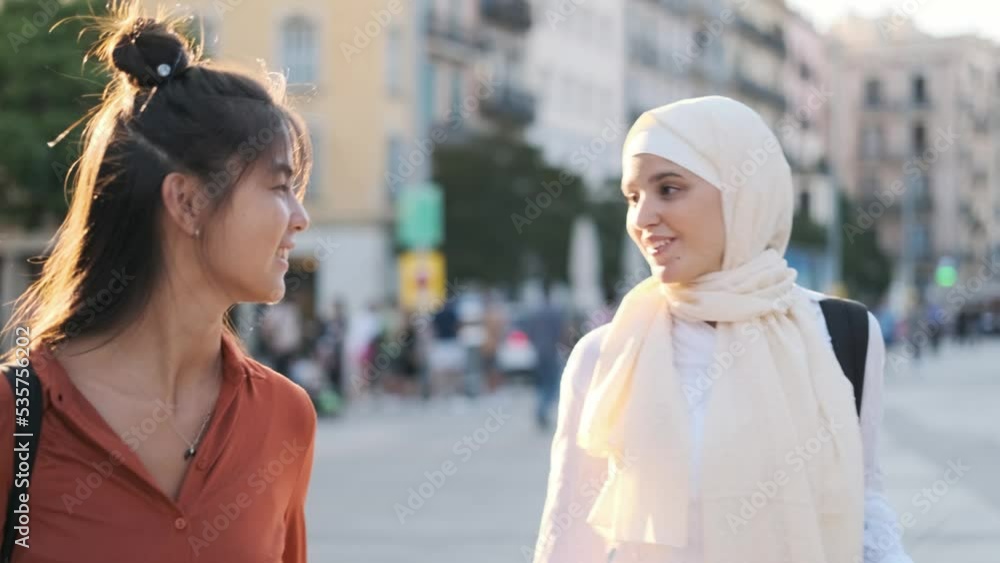 Young multiethnic friends talking and smiling while walking on the street. Young multiethnic friends talking and smiling while walking on the street.