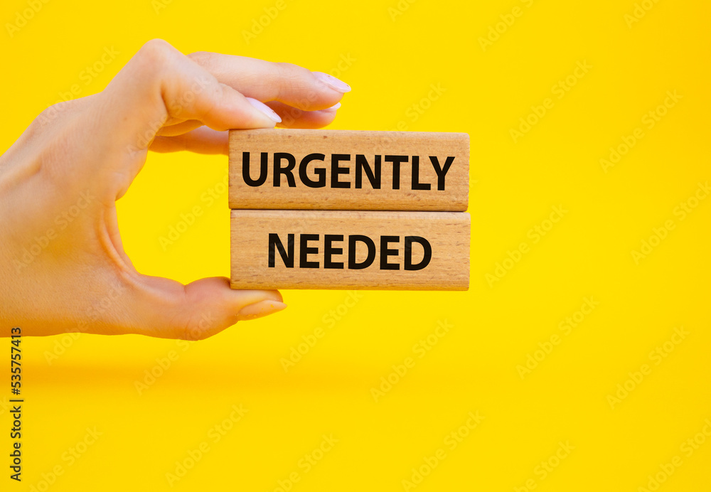 Urgently needed symbol. Concept word Urgently needed on wooden blocks. Beautiful yellow background. Businessman hand. Business and Urgently needed concept. Copy space Urgently needed symbol. Concept word Urgently needed on wooden blocks. Beautiful yellow background. Businessman hand. Business and Urgently needed concept. Copy space