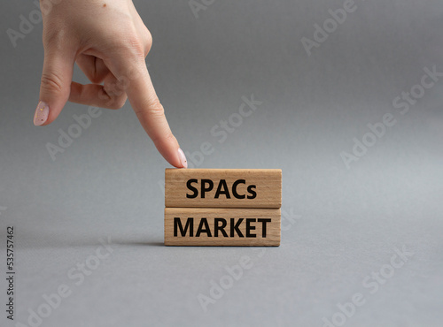 SPACs market symbol. Concept words SPACs market - special purpose acquisition companies market - on wooden blocks. Beautiful grey background. Businessman hand. Business concept. Copy space.