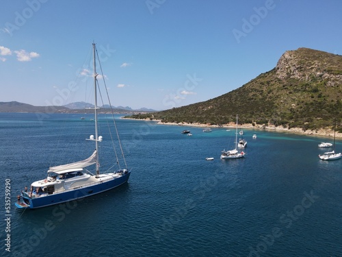Aerial view of Cala Moresca and Figarolo Island in Golfo Aranci  north Sardinia. Birds eye from above of yacht  boats  crystalline and turquoise water. Tavolara Island in the background  Sardegna.