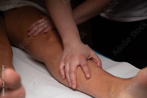 Massage in spa salon, foot massage, physiotherapist massaging girl's legs.