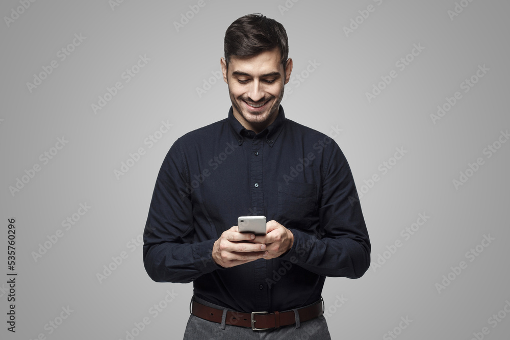 Portrait of cheerful businessman typing sms on smart phone, isolated on gray Portrait of cheerful businessman typing sms on smart phone, isolated on gray