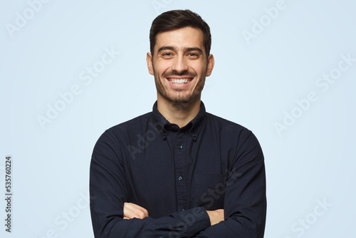 Attractive smiling business man in black shirt isolated on blue background