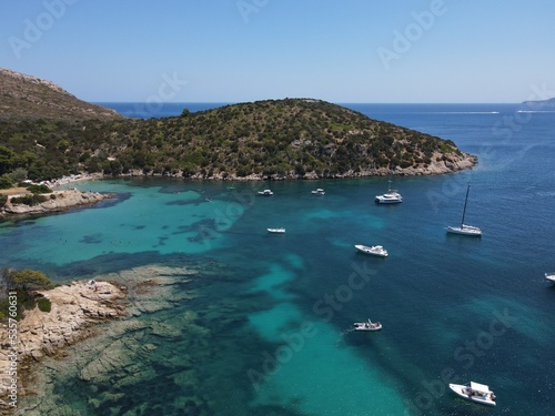 Aerial view of Cala Moresca and Figarolo Island in Golfo Aranci, north Sardinia. Birds eye from above of yacht, boats, crystalline and turquoise water. Tavolara Island in the background, Sardegna.