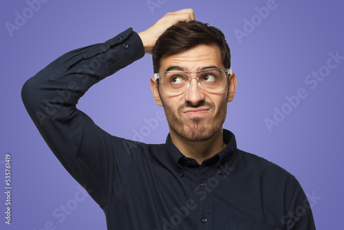 Caucasian man wearing glasses isolated on purple, scratching his head trying to find solution photo