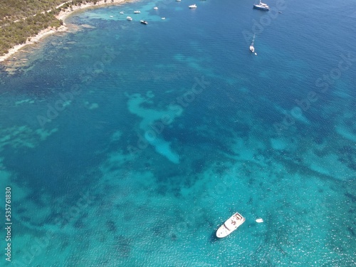 Aerial view of Cala Moresca and Figarolo Island in Golfo Aranci, north Sardinia. Birds eye from above of yacht, boats, crystalline and turquoise water. Tavolara Island in the background, Sardegna. © AerialDronePics