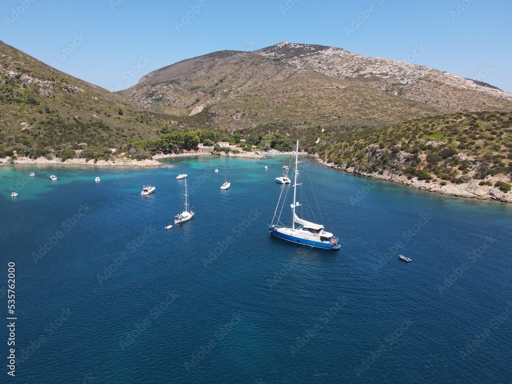 Aerial view of Cala Moresca and Figarolo Island in Golfo Aranci, north Sardinia. Birds eye from above of yacht, boats, crystalline and turquoise water. Tavolara Island in the background, Sardegna. Aerial view of Cala Moresca and Figarolo Island in Golfo Aranci, north Sardinia. Birds eye from above of yacht, boats, crystalline and turquoise water. Tavolara Island in the background, Sardegna.