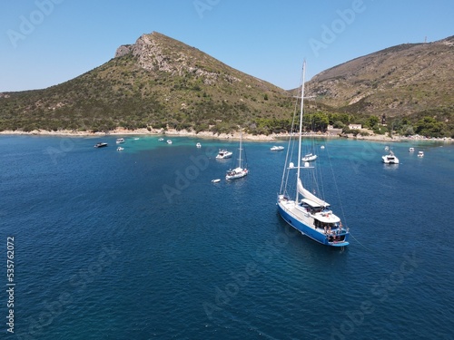 Aerial view of Cala Moresca and Figarolo Island in Golfo Aranci, north Sardinia. Birds eye from above of yacht, boats, crystalline and turquoise water. Tavolara Island in the background, Sardegna.