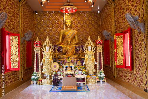 Ancient golden buddha statue in antique ubosot for thai people travelers travel visit and respect praying blessing to holy mystery worship at Wat Maniwong or Mani Wong temple in Nakhon Nayok, Thailand photo