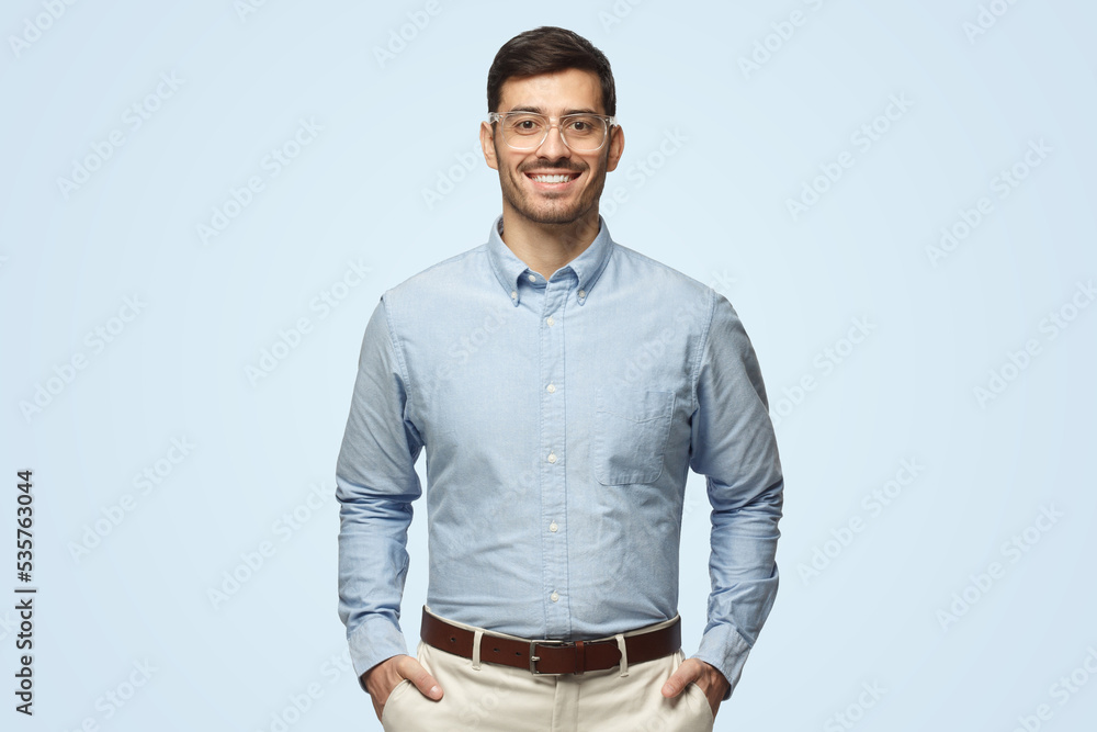 © Damir Khabirov - Smart businessman smiling at camera, wearing transparent glasses, isolated on blue background