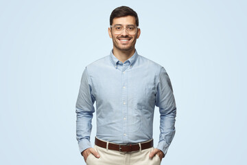 Smart businessman smiling at camera, wearing transparent glasses, isolated on blue background