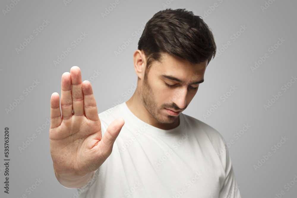 Photo of man pushing hand forward as if refusing something, wanting to stop, isolated on gray Photo of man pushing hand forward as if refusing something, wanting to stop, isolated on gray