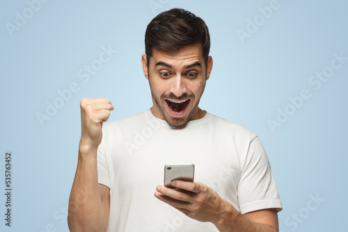 Happy guy holding phone having won something in Internet, perhaps in online casino