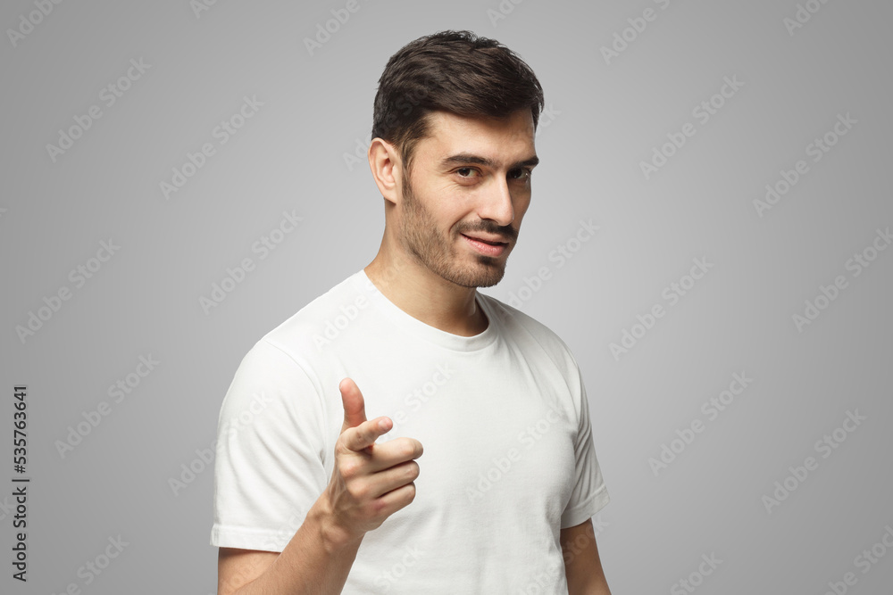 Young man pointing at camera on gray background Young man pointing at camera on gray background