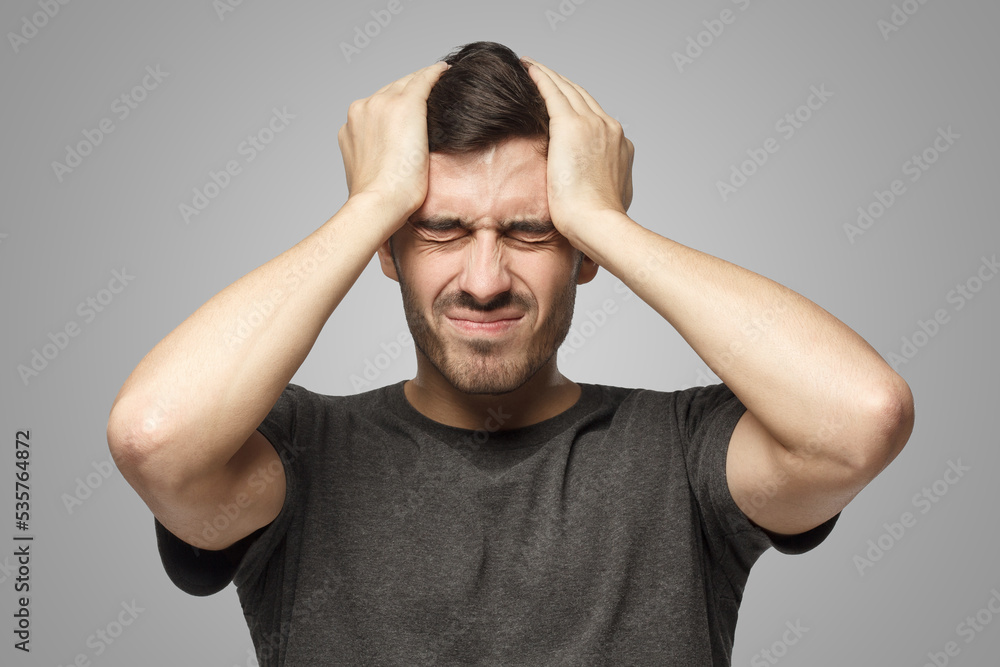 Man showing how much head hurts, experiencing pain, looking miserable and exhausted Man showing how much head hurts, experiencing pain, looking miserable and exhausted