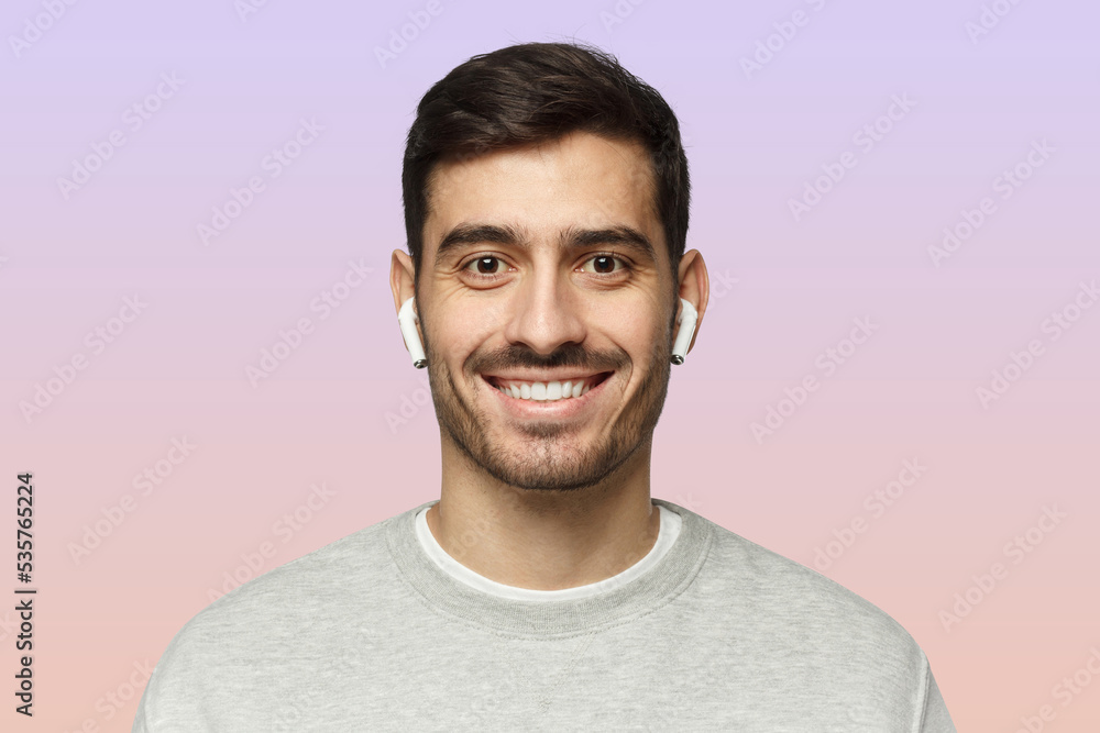 Close-up portrait of young smiling handsome man with earphones isolated on pink Close-up portrait of young smiling handsome man with earphones isolated on pink