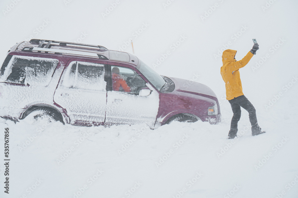 Woman recording from outside the car in the middle of a snow storm the damage of the traffic accident.