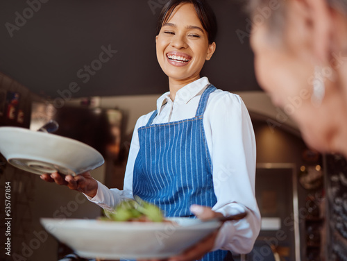 Waitress in a restaurant, serving customer her food, healthy salad and gives service with a smile. Woman in the hospitality industry, friendly laugh and happy to provide diet meal for lunch or dinner photo