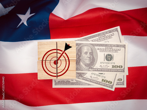 Top view of wooden cubes with darts target icon over US dollar banknotes on the American flag photo