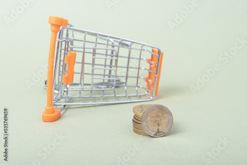 Turkish coins and small shopping cart on green background. Purchasing power photo