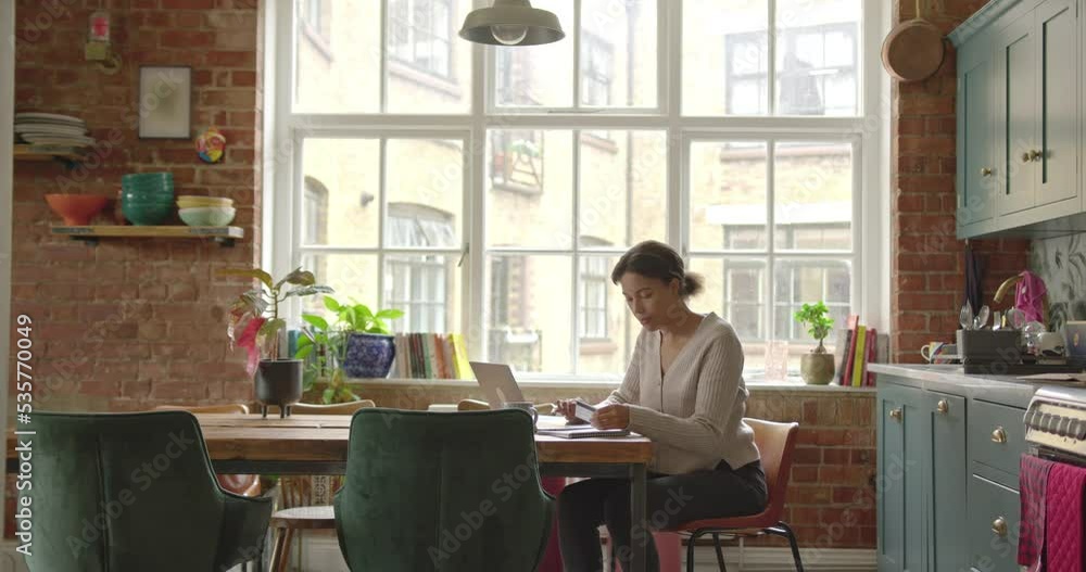 Young Adult Female at Home Paying Bills, Home Finance on Laptop in Kitchen Young Adult Female at Home Paying Bills, Home Finance on Laptop in Kitchen