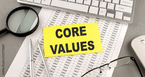 CORE VALUES text written on a sticky on chart with keyboard and magnifier photo