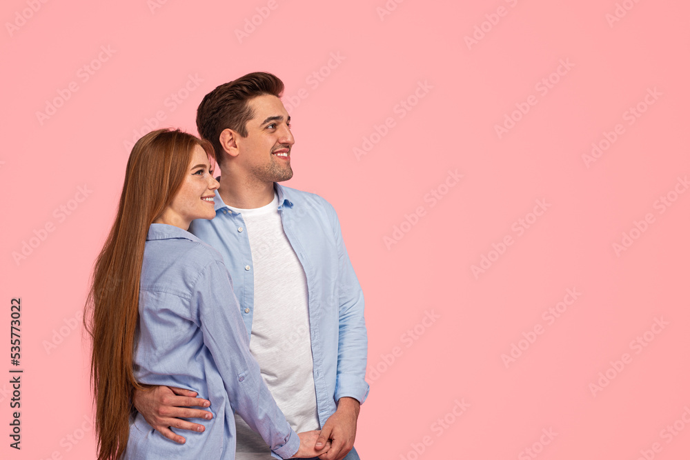 Happy beloved couple hugging and smiling in pink studio Happy beloved couple hugging and smiling in pink studio