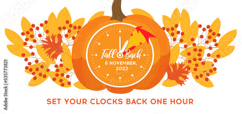 Daylight saving time, 2022 concept. Alarm clock and calendar with the date of November 6 on the pumpkin with autumn leafs decoration