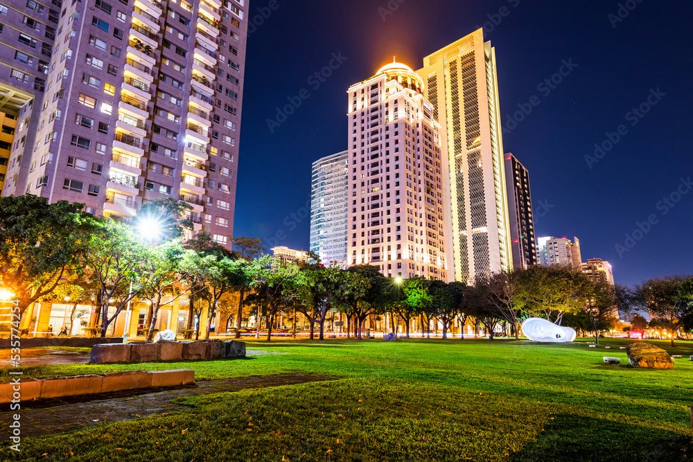 Obraz premium Low-angle view of green park space and modern buildings on both sides in downtown Taichung, Taiwan. here is near the National Taichung Theater.