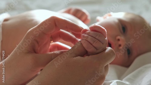 Baby hand in mother hands, on her palm. Happy parents holding their newborn baby tiny fingers, close up. Maternity, family, birth concept. Woman touching hand of infant baby. Mom and her Child. photo