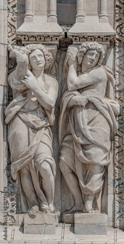 Two beautiful Roman women as decorative religious figures at facade of the Cathedral of Milano, Milan, Italy, closeup, details. Two beautiful Roman women as decorative religious figures at facade of the Cathedral of Milano, Milan, Italy, closeup, details.